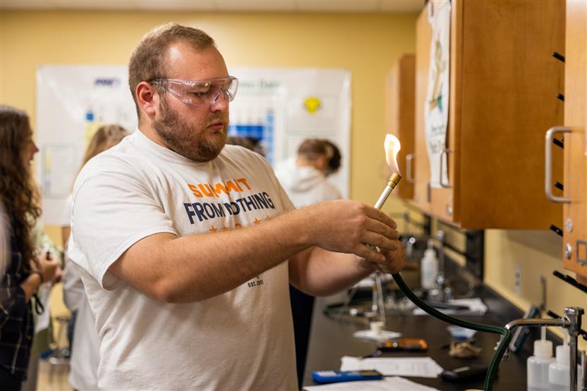 A teacher lights a Bunsen burner